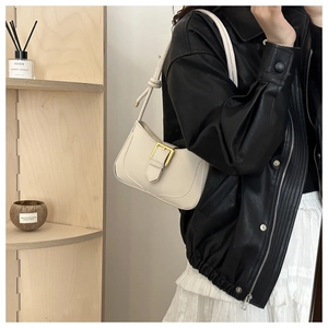 Sac baguette beige avec boucle dorée et bandoulière nouée porté par un mannequin