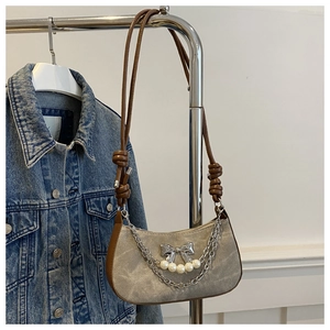 Détail du sac sous le bras en toile avec nœud argenté, perles blanches et double chaîne
