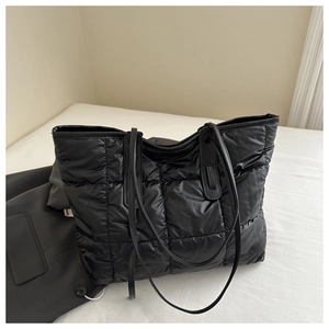 Close-up of black quilted tote bag texture with high-gloss nylon finish and grid stitching