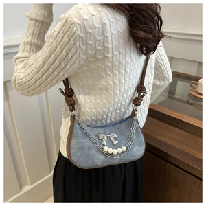 Détail du sac en denim bleu avec nœud argenté et pendentif en perles élégant