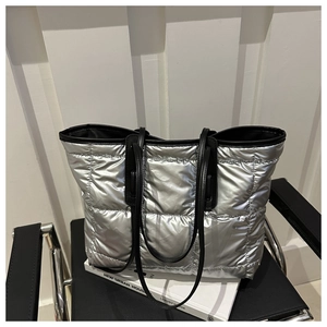 Detail of silver quilted tote bag with metallic finish and black shoulder straps