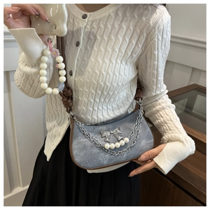 Détail du sac hobo en jean bleu avec nœud argenté et bandoulière en perles