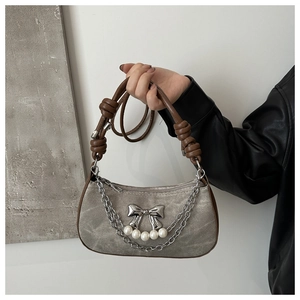 Detail of grey washed denim baguette bag with silver bow and pearl chain charm