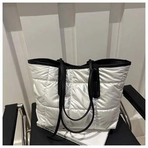 Detail showing white puffy quilted texture and black straps of the large tote bag