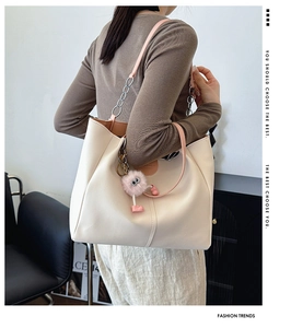Large cream PU tote bag featuring pink straps, metal chains, and a plush monster charm