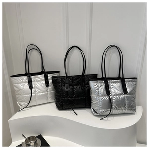 Three quilted puffer tote bags in white black and silver shown on a minimalist display