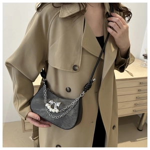 Gros plan du sac demi-lune gris avec chaînes argentées et pendentif nœud en perles