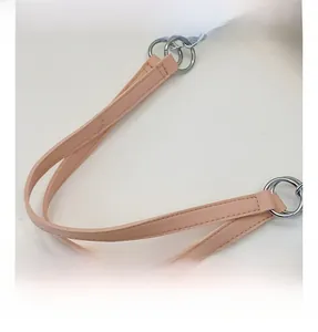 Detail of pink faux leather tote bag handle with silver metal rings and double stitching