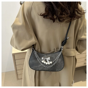 Detail of dark grey crescent shoulder bag with silver chains, bow and pearl accents