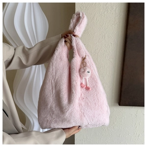 Détail du cabas en peluche rose avec texture douce et charmant pompon en forme d'oeil