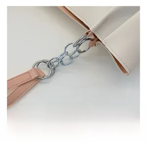 Detail view of the silver multi-link metal chain and pink leather handle on a tote bag