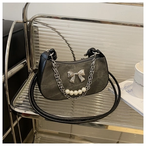 Close-up of a grey crescent shoulder bag featuring a silver bow and pearl chain detail