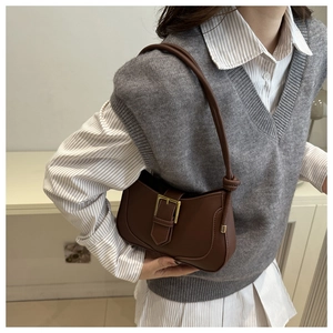 Détail du sac porté épaule marron avec boucle dorée et bandoulière nouée élégante