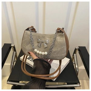 Detail of silver bow and pearl chain on a textured taupe crescent shoulder bag
