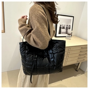 Black quilted puffer tote bag with long shoulder straps for casual autumn fashion style