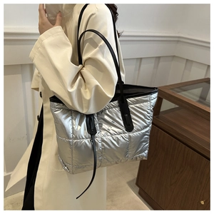 Detail of silver quilted tote bag with large square stitching and black leather handles