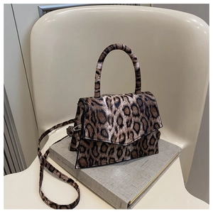 Macro detail of leopard print faux fur texture and round handle on a chic crossbody bag