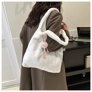 Détail de la texture d'un sac cabas en fausse fourrure blanche avec pompon rose