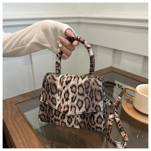 Detail of leopard print handbag featuring a unique circular handle and V-shaped flap cover