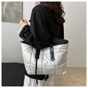 Detail of white quilted tote bag with silver metallic finish and black shoulder straps