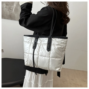 Close-up of white quilted tote bag featuring black leather straps and contrast trim