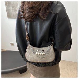 Detail of grey shoulder bag with silver bow charm, pearls, and metal chain decoration