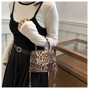 Detail shot of mini leopard print handbag with sleek top handle and crossbody strap