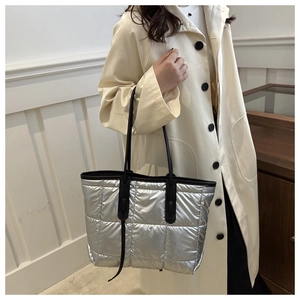 Detail of silver quilted puffer tote bag with black shoulder straps and metallic finish