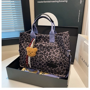 Detailed leopard print canvas tote bag with purple straps and plush bear charm accent