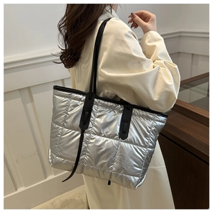 Detail of silver quilted tote bag with metallic finish shown on a model's shoulder
