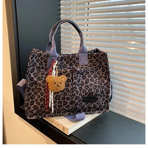 Detailed view of leopard canvas tote featuring purple straps and a brown plush bear charm