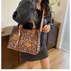Close-up of leopard print canvas tote with bear charm and silk scarf detail