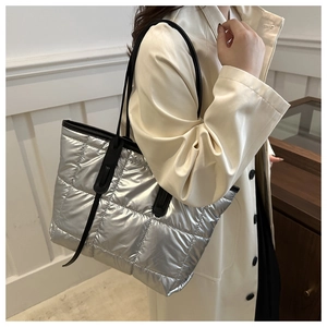 Detail of silver quilted tote bag with metallic texture and black shoulder straps