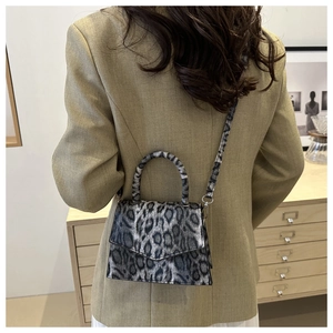 Back view of leopard print crossbody bag on model wearing a beige blazer jacket