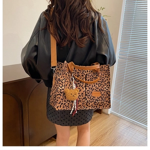 Close-up of leopard print canvas tote bag with brown straps and plush bear charm