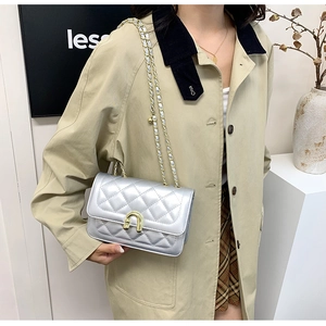 Silver quilted crossbody bag with gold hardware shown on model with beige coat