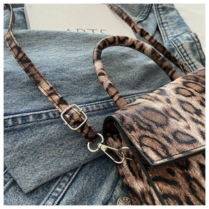 Detailed close-up of leopard print handbag with metal clasp and adjustable strap textures