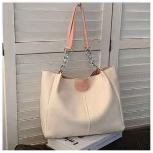 Detail of a large capacity tote bag with pink leather handles and silver chain link