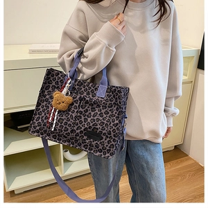 Detail of leopard print tote bag with purple straps and plush bear charm for daily use