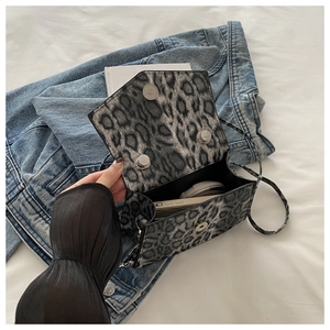 Detail view of the double magnetic closure and interior space of a leopard print square bag