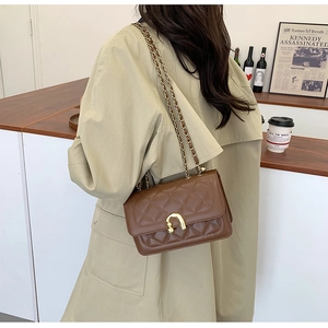 Dettaglio della borsa in pelle marrone trapuntata con chiusura a U dorata e tracolla a catena