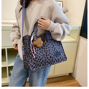 Detail of purple leopard canvas tote with bear pendant and crossbody strap