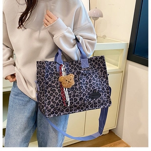 Detail of leopard print canvas tote bag featuring purple straps and plush bear charm