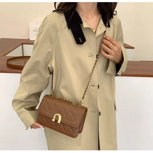 Detail of vintage brown quilted crossbody bag featuring golden horseshoe twist lock