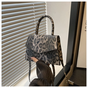 Detail of leopard print handbag showing matte texture and sturdy handle from a side angle