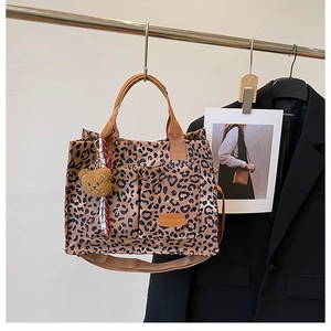 Detail of leopard print canvas tote bag featuring multiple pockets and bear charm