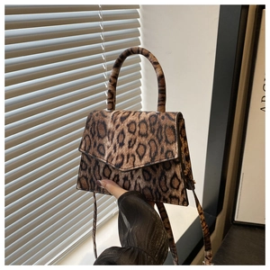 Detail of leopard print crossbody bag with curved handle and adjustable strap in hand