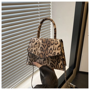 Detail of a leopard print handbag with a triangular flap and a sleek curved handle