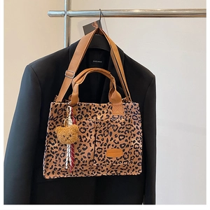 Detail of leopard print canvas tote with external pockets and plush bear charm accent