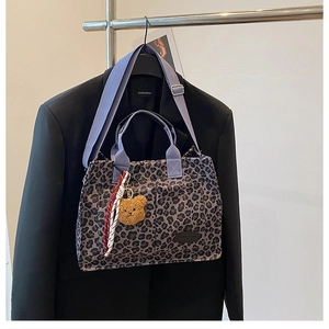 Detail of leopard print canvas tote bag with purple straps and cute bear charm
